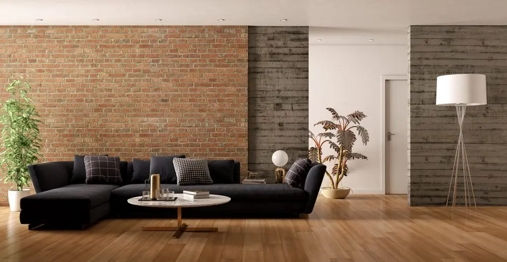 modern living room interior with a black sectional sofa, a round marble coffee table, and a mix of textures on the walls, including exposed brick and concrete panels